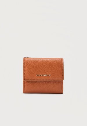 Small folded brown leather wallet with grain texture and gold "COCCINELLE" logo on front flap.