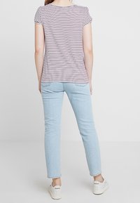Stribet kortærmet t-shirt i hvid og rød, parret med lyseblå tætsiddende jeans og hvide sneakers. Blødt stof med glat tekstur.
