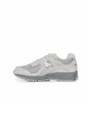 Sneaker atletica grigia con pannelli in suede e mesh, design con lacci e suola spessa e testurizzata, vista laterale che mostra il logo sul lato.