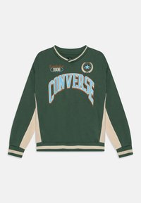 Sudadera verde con el texto "CONVERSE" en blanco y naranja, detalles en beige en las mangas, puños y cuello acanalados, y la fecha de establecimiento 1908.
