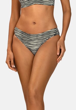 Kobieta ubrana w bikini z poziomymi czarno-białymi paskami na dole i dopasowanym topie, stojąca na jednolitym tle.