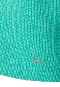 Strickpullover in strahlendem Türkis, mit einem strukturierten Rippdesign und einem kleinen silbernen Markenschild nahe dem Saum.