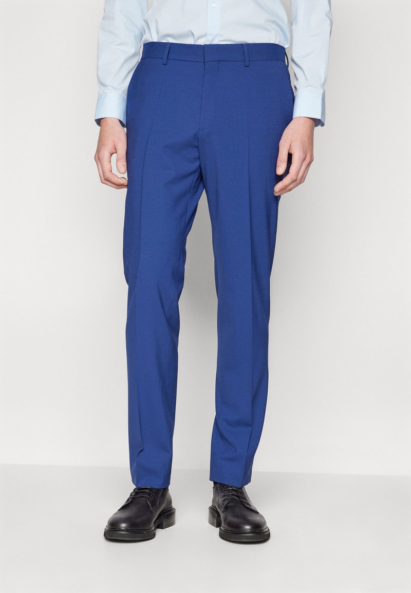 Op maat gemaakte blauwe broek van soepele, lichte stof met een slanke pasvorm, voorzien van riemlussen en een plooi aan de voorkant.