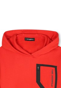 Sweatshirt à capuche rouge en tissu doux, avec une poche zippée noire et un logo imprimé dans une couleur contrastante.