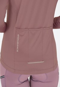 Achterkant van een mauve sportjack en legging, met drie achterzakken en de tekst "ENDURANCE" op de linkerzak.