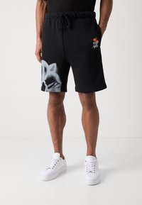 Shorts de sport noirs en coton, avec un motif gris d'un c ôté et un logo coloré brodé. Longueur mi-thigh avec des poches latérales.