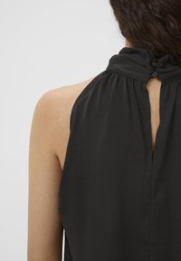 Svart halterneck-top med plisserad halsringning, nyckelhålsöppning i ryggen och två knappar för stängning. Slät textur och lättviktsmaterial.