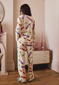 Sæt i bomuld med pyjamas, der har en cremefarvet baggrund og farverige candy-mønstre i rød, grøn, lilla og blå; blød ribbet tekstur.