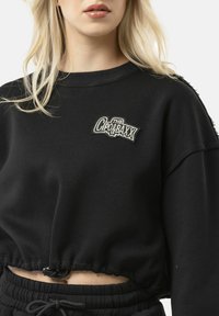 Zwarte cropped sweatshirt van katoen. Kenmerkt een geribde halslijn, ruime pasvorm en een geborduurd logo. Textuur lijkt zacht en ontspannen.