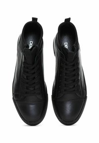 Czarne trampki z teksturowaną skórzaną cholewką, gładkim noskiem i płaskimi czarnymi sznurówkami. Minimalistyczny design z pętelką z tyłu.