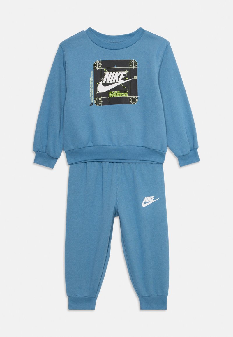 Blaues Nike-Sweatshirt- und Jogginghosen-Set. Das Sweatshirt hat ein schwarzes Logo-Design; die Hose hat ein weißes Logo und einen elastischen Bund aus weichem Material.