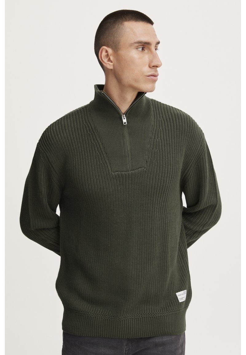 Donkergroen gebreid sweater met een halve ritssluiting bij de kraag, voorzien van een gestreept patroon op het lijfje en een klein label aan de zoom.