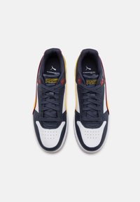 Navy and white sneakers with textured leather, perforated toe, red and yellow accents, flat laces, and padded collar.