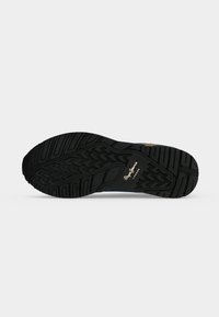 Semelle de chaussure en caoutchouc noir avec motif de bande de roulement texturé et logo "Pepe Jeans London" visible en blanc sur la zone de la voûte plantaire.