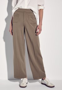Breda khaki-byxor i mjukt material, med två bakfickor och en slät, ren midja. Parat med vita sneakers.