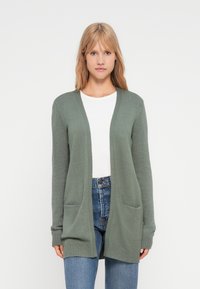 Cardigan verde deschis cu o croială lejeră, având mâneci lungi, deschidere frontală și două buzunare frontale. Fabricat dintr-un material tricotat moale și texturat.