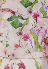 Tissu floral aux couleurs pastel douces, présentant diverses fleurs et des feuilles vertes. Des couches transparentes ajoutent de la texture avec des détails délicats.