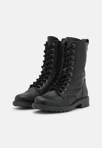 Bottines en cuir noir avec une finition texturée, à lacets à l'avant et fermeture éclair sur le côté, avec des œillets métalliques et une semelle en caoutchouc robuste.