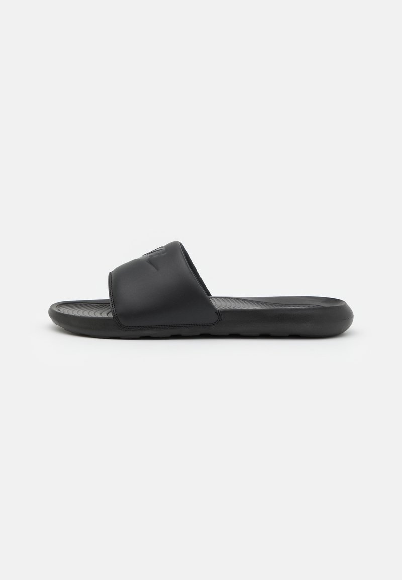Sandale à enfiler noire avec une large bride sur le pied et une semelle intérieure texturée sur fond blanc uni.