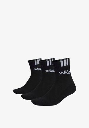 Czarne skarpetki sportowe z prążkowanymi ściągaczami, z białymi akcentami w postaci trzech pasków oraz logo "adidas". Gładka struktura i długość crew.