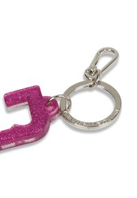 Chaveiro de resina com glitter rosa em forma da letra "J", preso a um anel de metal prateado com detalhe de logotipo gravado.