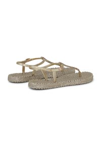 Sandalias planas beige con suelas tejidas texturizadas y tiras finas con pequeños detalles decorativos y hebillas ajustables.