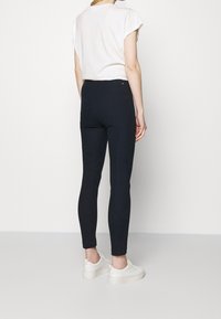 Hoge taille, elegante zwarte leggings gemaakt van rekbaar materiaal, gecombineerd met een losse witte t-shirt en witte sneakers. Schone, minimale uitstraling.