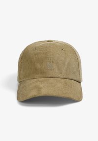 Gorra de béisbol de pana en color beige claro con una corona redondeada y visera curva. Presenta un logotipo bordado de calavera y tibias cruzadas en el frente.