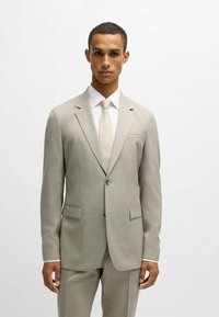 Completo grigio chiaro con vestibilità slim, motivo testurizzato sottile, rever a scollo, due tasche frontali e chiusura a un bottone.