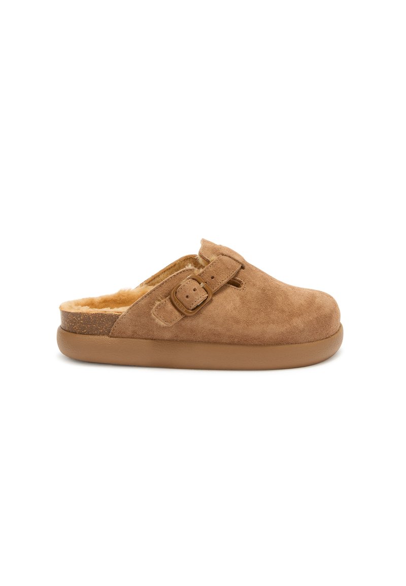 Brune suede slip-on klip med en blød pelsfor, justerbar rem og en lys brun gummisål. Glat tekstur med en rund tå.