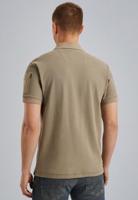 Korte mouwen polo shirt van olijfgroen katoen, met een kraag, schouderpatch en subtiele stikdetails. Soepele textuur, getailleerd ontwerp.