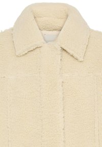 Τζάκετ sherpa fleece σε κρεμ αποχρώση με διπλωμένο γιακά και ορατές ραφές μπροστά.