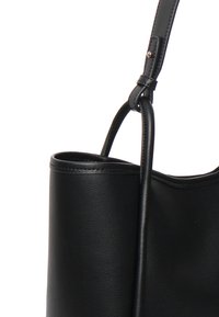 Sort læder tote taske med en glat tekstur, designet med en rund åbning og et langt, justerbart skulderrem. Minimalistisk og moderne stil.