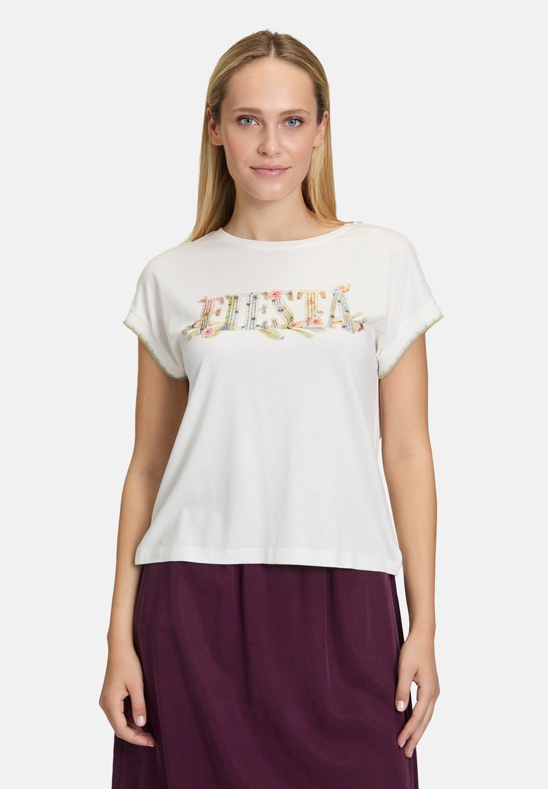 Hvid bomulds t-shirt med korte, rullede ærmer og "Fiesta" broderet i farverig blomsterdesign over brystet.