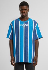 Mėlynos ir baltos dryžuotos per didelės t-shirts su apvalia kaklo iškirpte ir prekės ženklo pavadinimu 'KANI', atspausdintu centre. Pagaminta iš minkštos medžiagos.