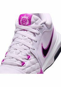 Lyse lilla atletisk sko med strukturstof, pink detaljer og sort swoosh-logo. Har en polstret sål og quiltet design.