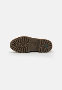 Rubber boot sole featuring deep grooves for traction, a prominent logo, and a solid brown color. Textured surface for added grip.