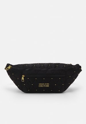 Černá prošívaná ledvinka s malými zlatými cvočky, přední kapsa na zip, zlaté zipy a logo „Versace Jeans Couture“ ve zlatých písmech.