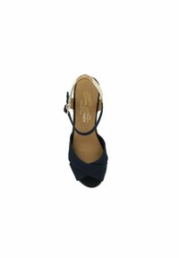 Navy blue high-heel sandal featuring crossed fabric straps, an open toe, and a beige ankle strap with a buckle. Textured sole visible.