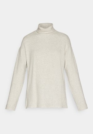 Turtleneck sweater in light beige, featuring long sleeves, ribbed texture, side slits, and a relaxed fit. Made from a soft knit material.