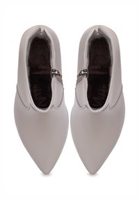 Szegecsőrű bokacsizmák világosszürke szintetikus anyagból. Oldalcipzárral és sima textúrával rendelkezik, finom varrási részletekkel.