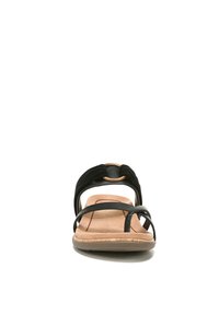 Black sandal with multiple crisscross straps, cushioned insole, and a light brown textured sole. Features a decorative circular accent.