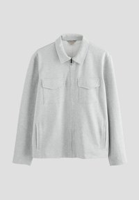 Chaqueta gris con cremallera, hecha de tela suave, con cuello tipo solapa, dos bolsillos en el pecho y aberturas laterales para mayor comodidad.