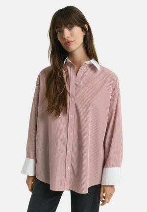 Red and white striped shirt with long sleeves, button closure, and a contrasting white collar. Made from a smooth fabric, relaxed fit.