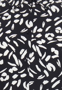 Zwarte overhemden met knopen, voorzien van een wit abstract patroon, met een puntige kraag en een gladde textuur, geaccentueerd door zwarte knopen.