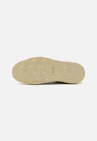 Suela de zapato en beige claro con un patrón de zigzag texturizado. Presenta la marca en relieve "JACK & JONES" cerca del centro. Diseño plano y duradero.