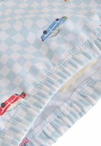 Blauw-wit geruit stof met kleine rode en blauwe autobezettingen. Elastische tailleband met zichtbare stiksels. Zachte textuur.