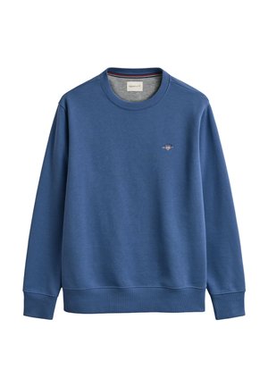 Hanorac bleu cu mâneci lungi, guler rotund, cu manșete și tiv elastic, având un mic logo GANT brodat pe partea stângă a pieptului.