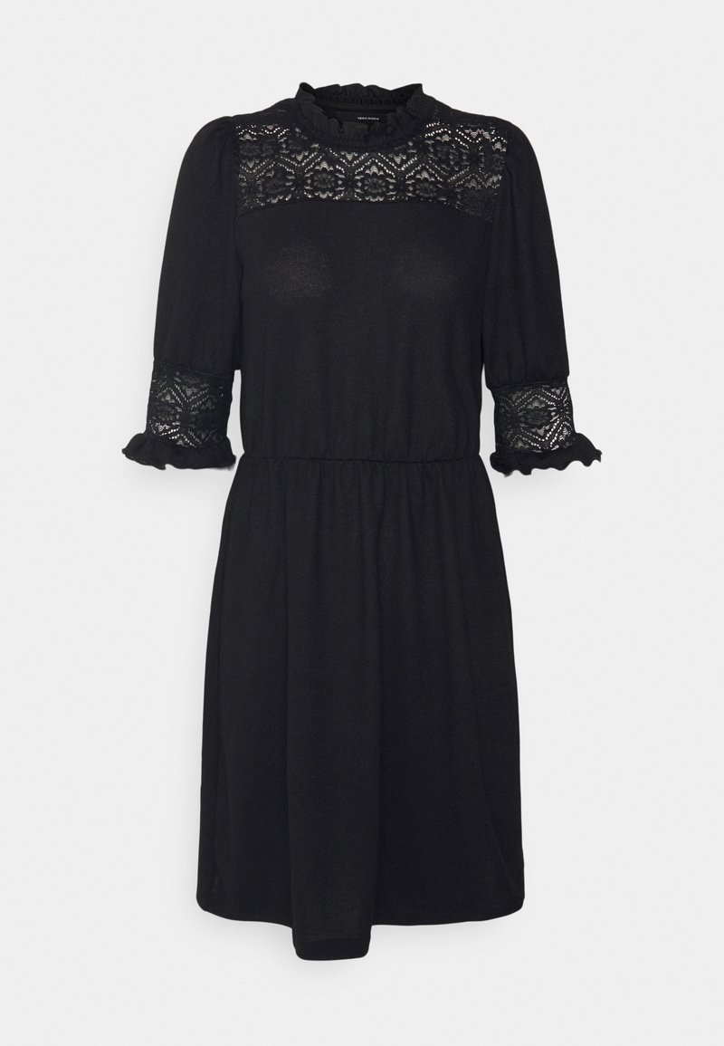 Robe noire longueur genou avec panneaux en dentelle sur le haut de la poitrine et les manches, poignets à volants et taille froncée, présentée sur fond blanc.