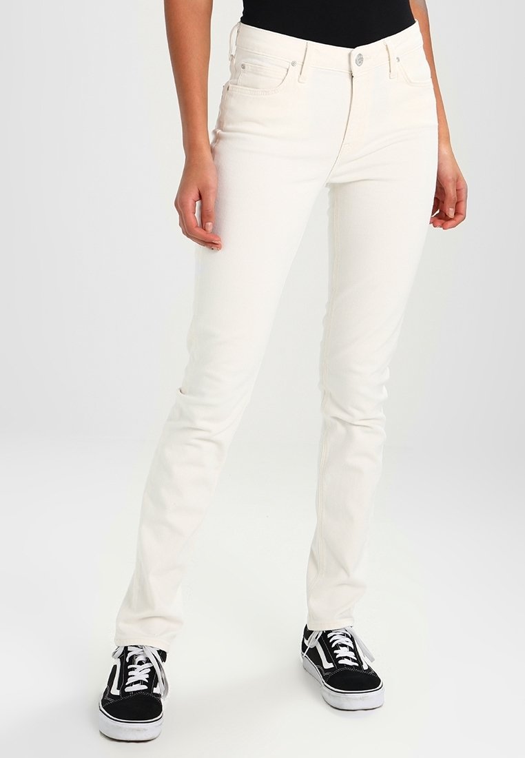 Jeans blancs slim en denim, avec fermeture à bouton et zip, cinq poches et une texture lisse. Portés avec des baskets noires.